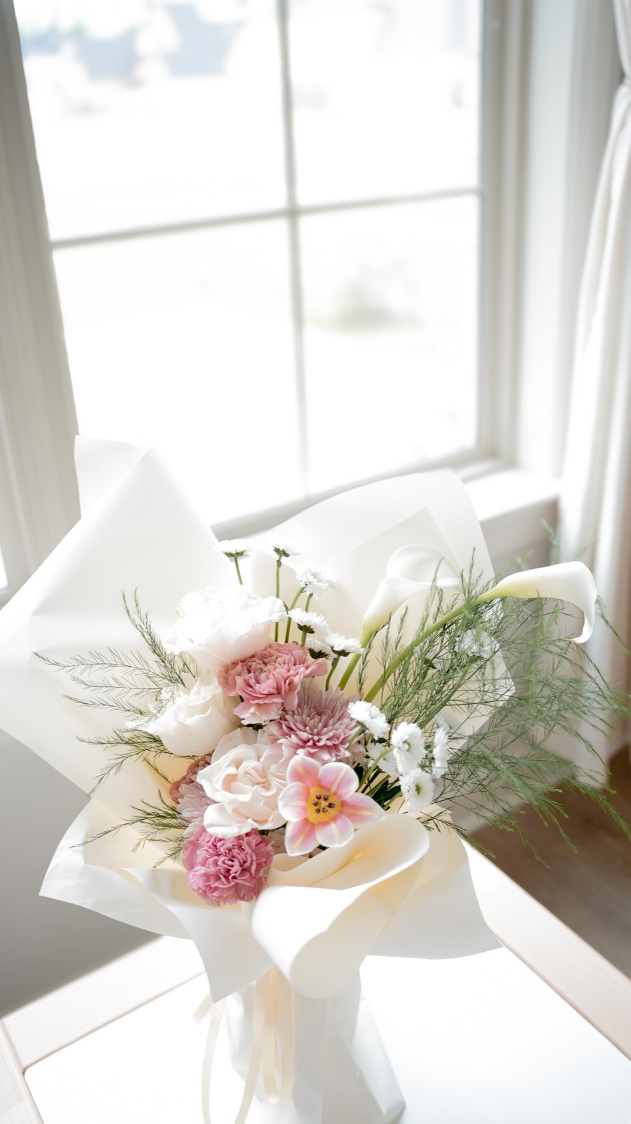 Blush Meadow bouquet — blush roses, pink carnations, white calla lilies, chrysanthemums, daisies in cream wrap